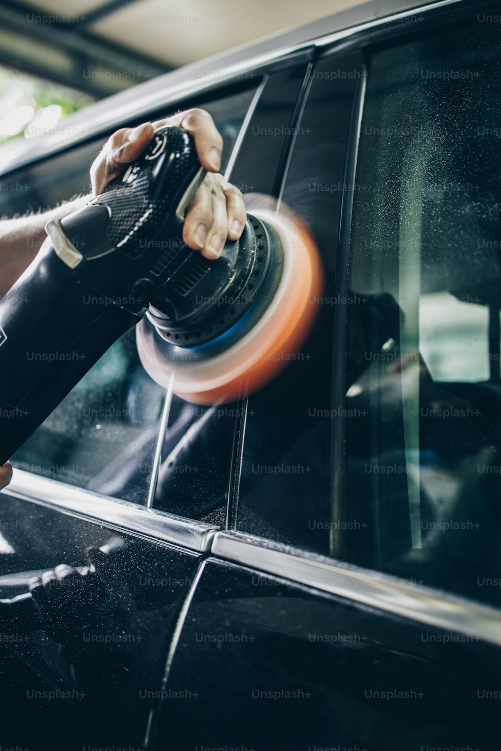 Car detailing - Hands with orbital polisher in auto repair shop. Selective focus.