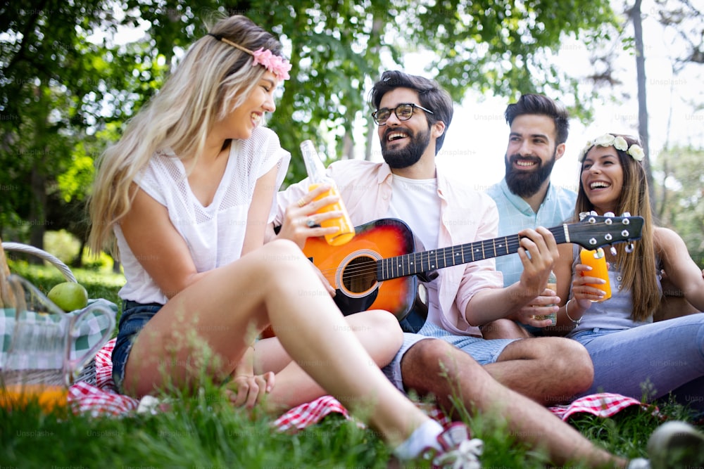 Happy young friends having picnic in the park. People ,having fun, smiling, playing guitar concept
