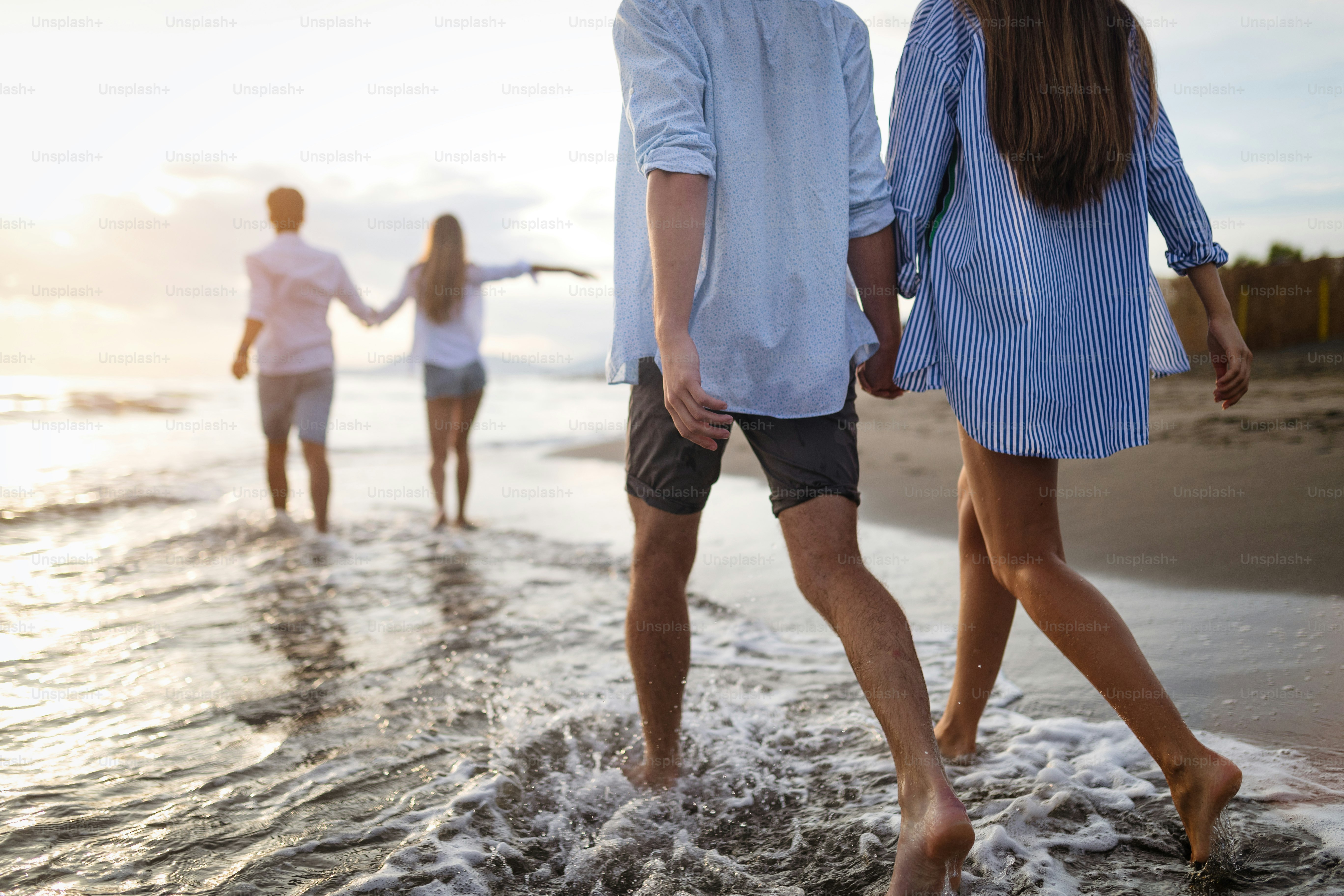 Gruppo di amici che si divertono sulla spiaggia sotto la luce del tramonto.