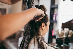 美容院で長い髪の美しいブルネットの女性が髪を吹いています。ヘアサロンのスタイリングコンセプト。