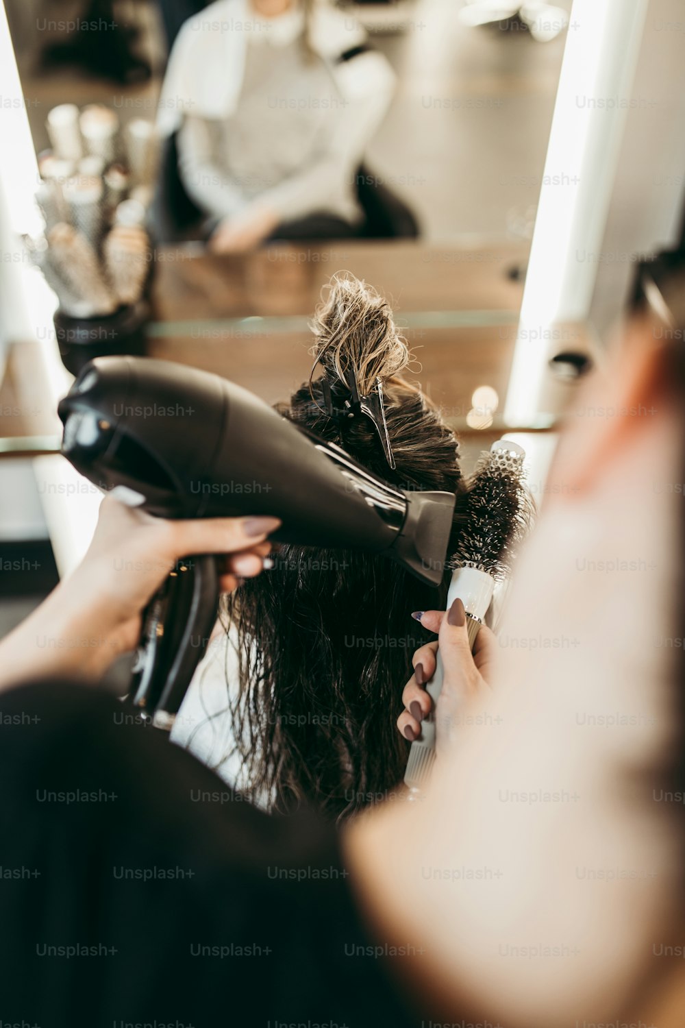 Beautiful brunette woman with long hair at the beauty salon getting a hair blowing. Hair salon styling concept.