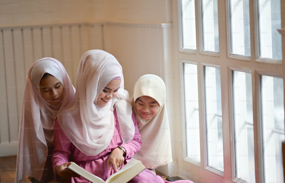 Young Asian Muslim teaching her sister to reading a book