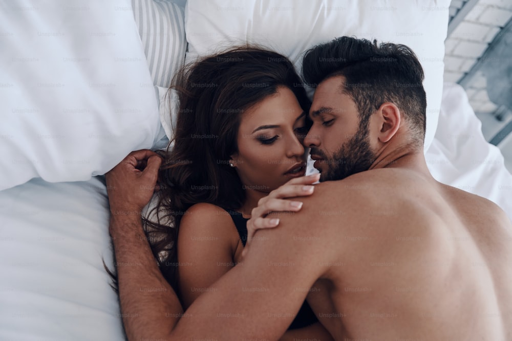 Vista superior de una hermosa pareja joven haciendo el amor mientras está acostado en la cama
