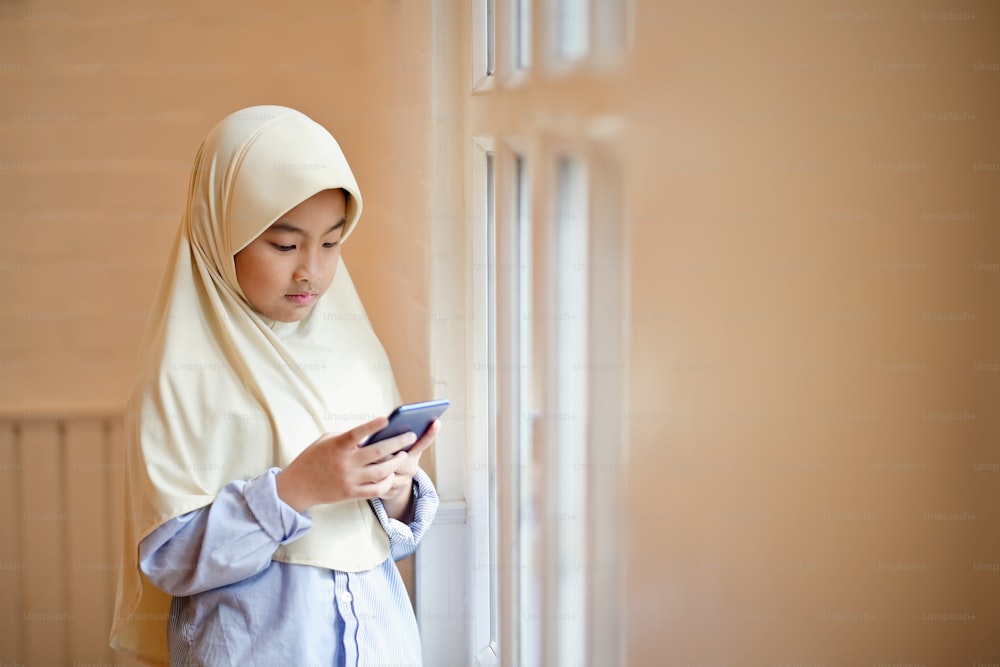 Asian Muslim girl using, text sms mobile phone.