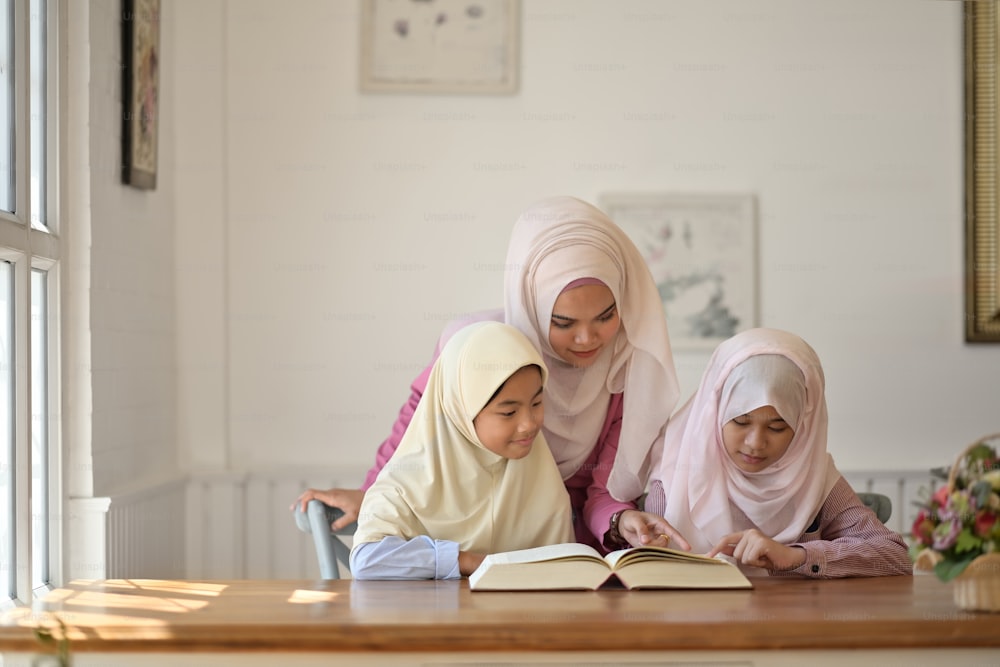 Young Asian Muslim teaching her sister to reading a book