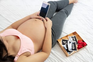 Mulher grávida sentindo-se feliz em casa enquanto cuida de seu filho. A jovem mãe grávida segurando o bebê na barriga grávida. Pré-natal da maternidade e conceito de gravidez da mulher.