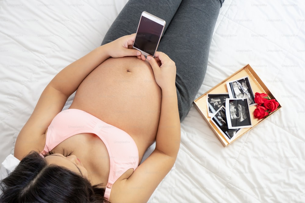 임신한 여자는 아이를 돌보며 집에서 행복을 느낀다. 임신한 뱃속에 아기를 안고 있는 젊은 임산부. 출산 산전 관리 및 여성 임신 개념.