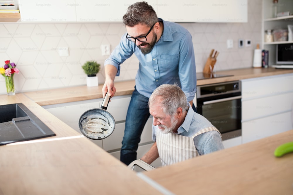 성인 힙스터 아들과 노인 아버지는 집 부엌에서 실��내에서 요리를 하고 있습니다.