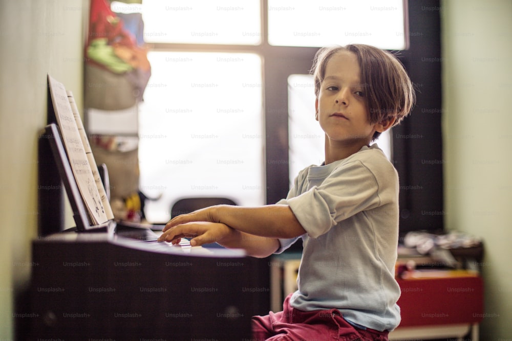 Orgulhoso de seu progresso musical. Garotinho jogando piano.