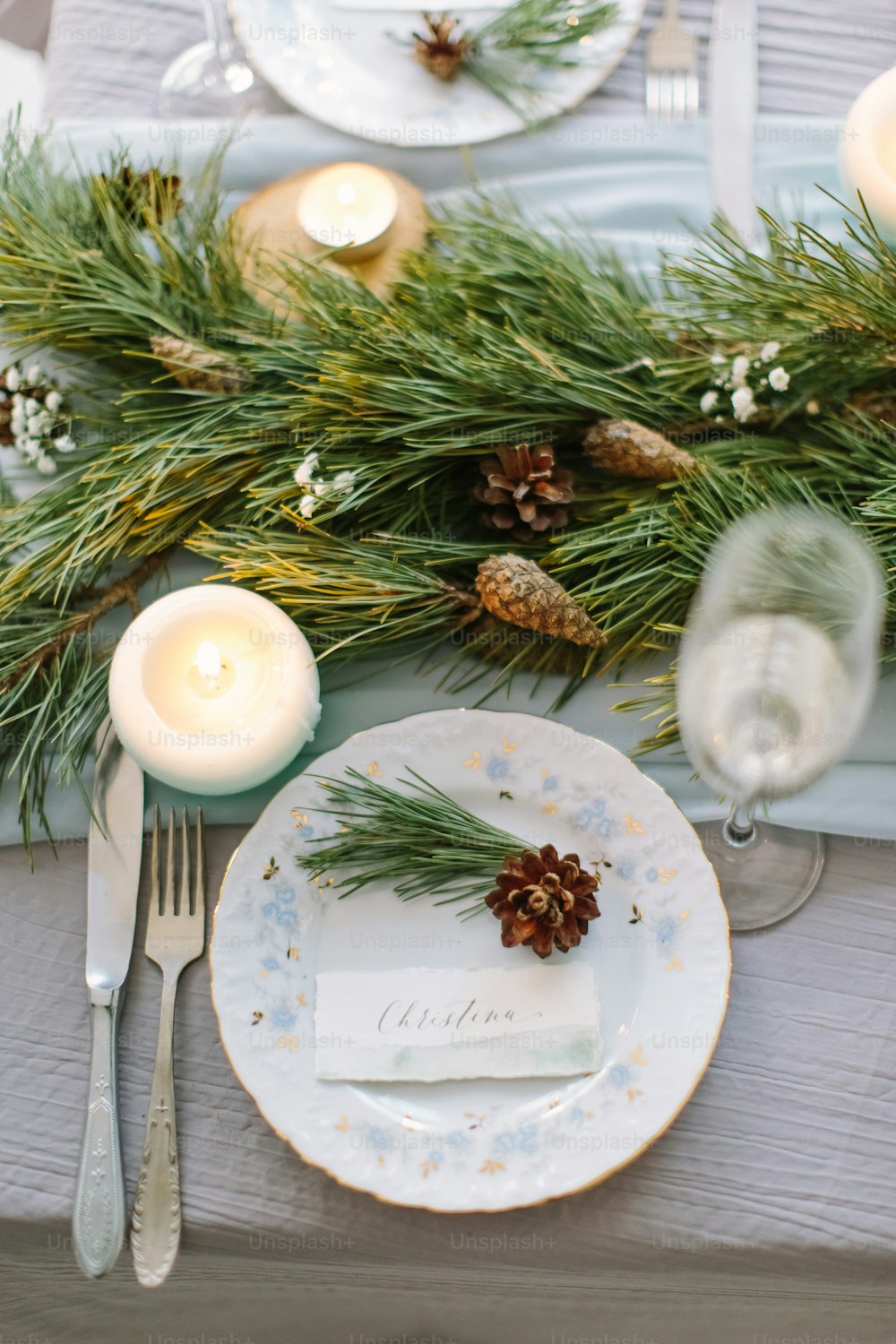 Aerial view of winter green garland on a wedding table with white plates and and blue candles