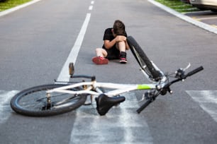 Adolescente Há uma lesão no joelho, pois a bicicleta cai durante a pilotagem. Garoto machucou a perna depois de cair da bicicleta