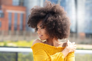 Portrait of young african american woman with curly hair posing in the city street.