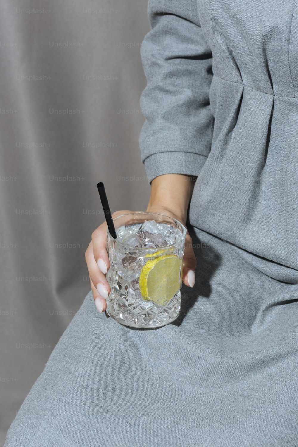 Frau mit Gin Tonic, grauem und stimmungsvollem Hintergrund