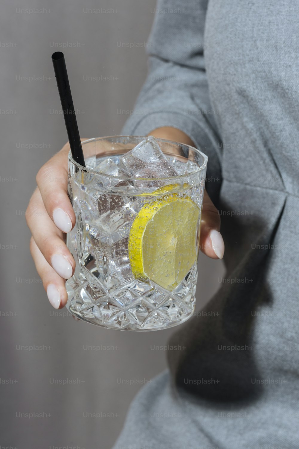 Donna che tiene gin tonic, sfondo grigio e lunatico