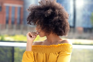 Portrait of young african american woman with curly hair posing in the city street.