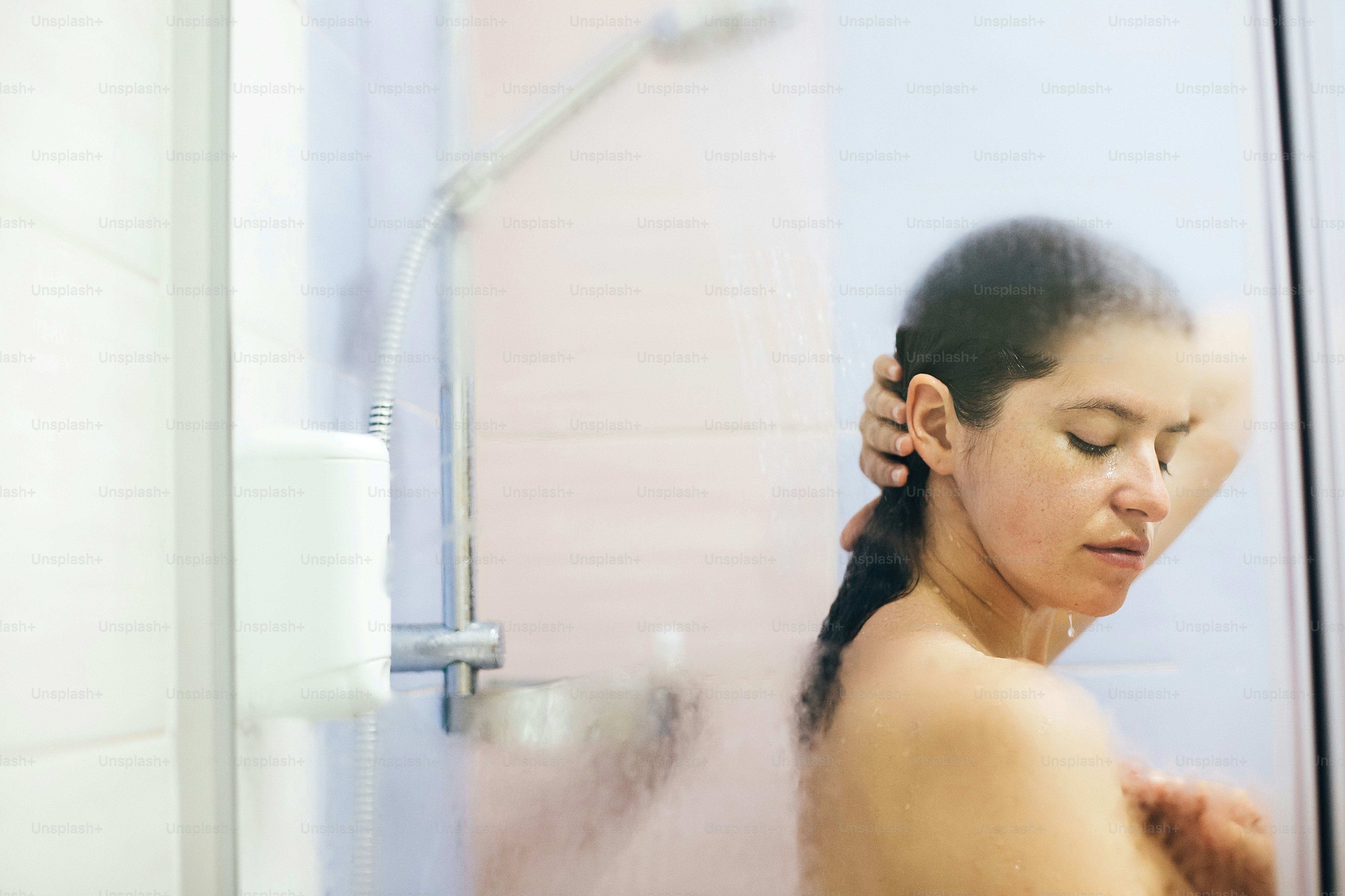 Young happy woman washing her hair, washing away shampoo foam. Portrait of beautiful brunette girl taking shower and enjoying time. Body and hair hygiene, lifestyle concept. Space text
