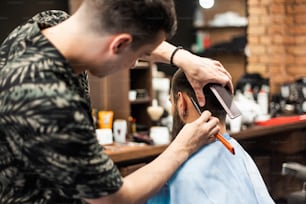 Razor in hands of professional barber. Hairdresser shaving man's neck with a straight razor