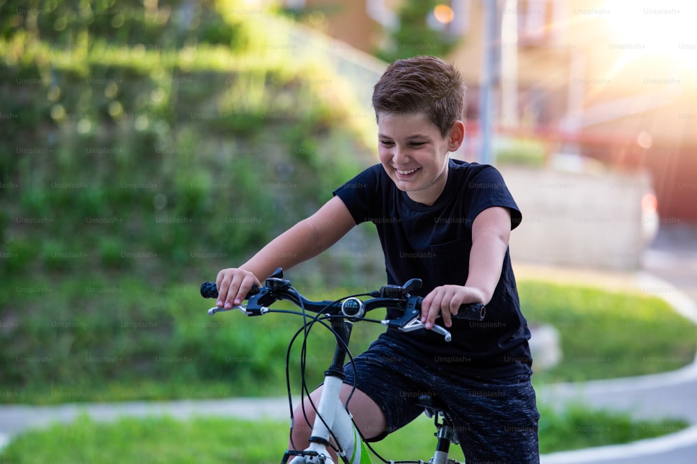 Happy boy riding bike at sunset. Smiling child on bicycle into the sun