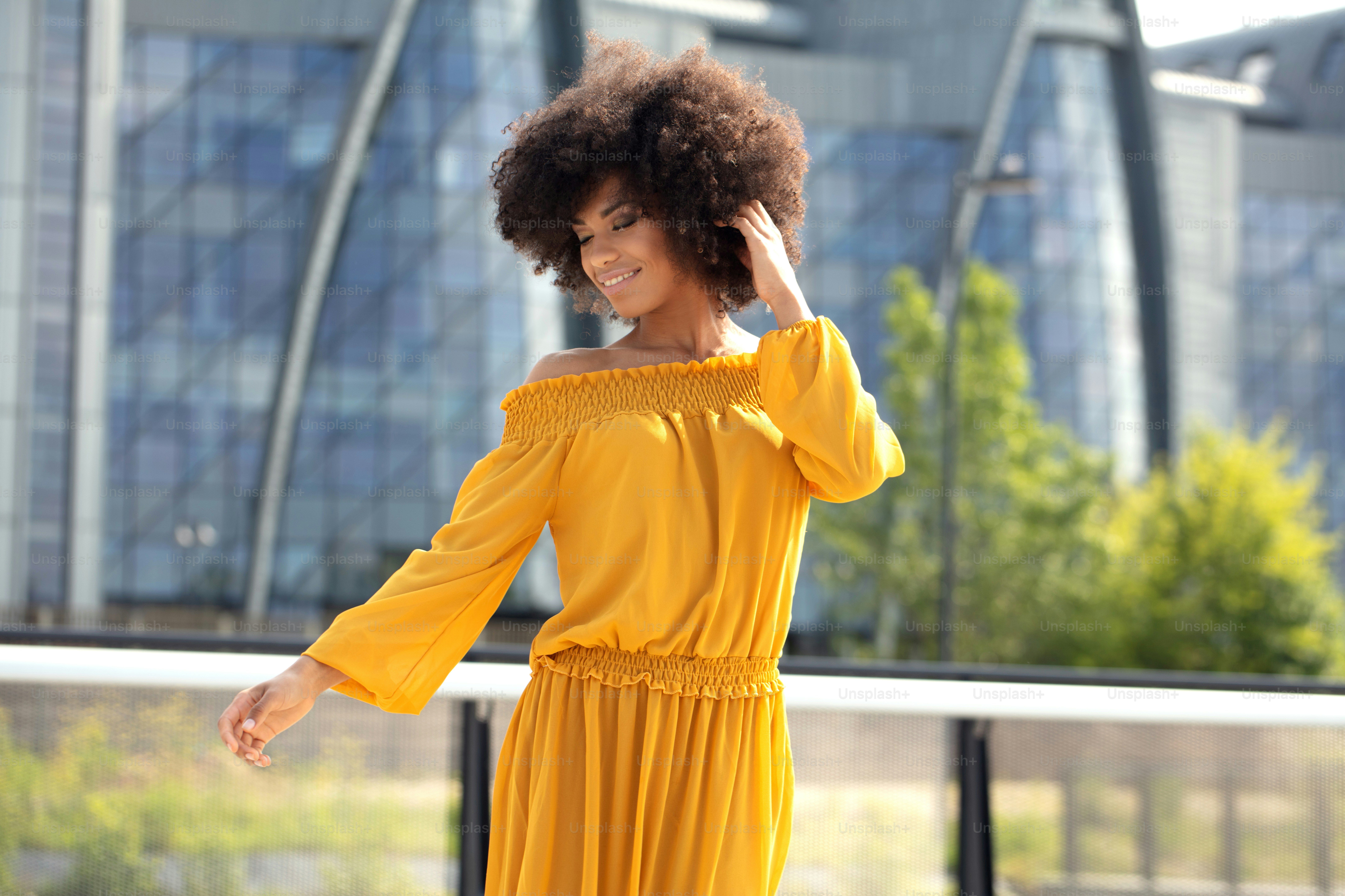 Portrait of young african american woman with curly hair posing in the city street.