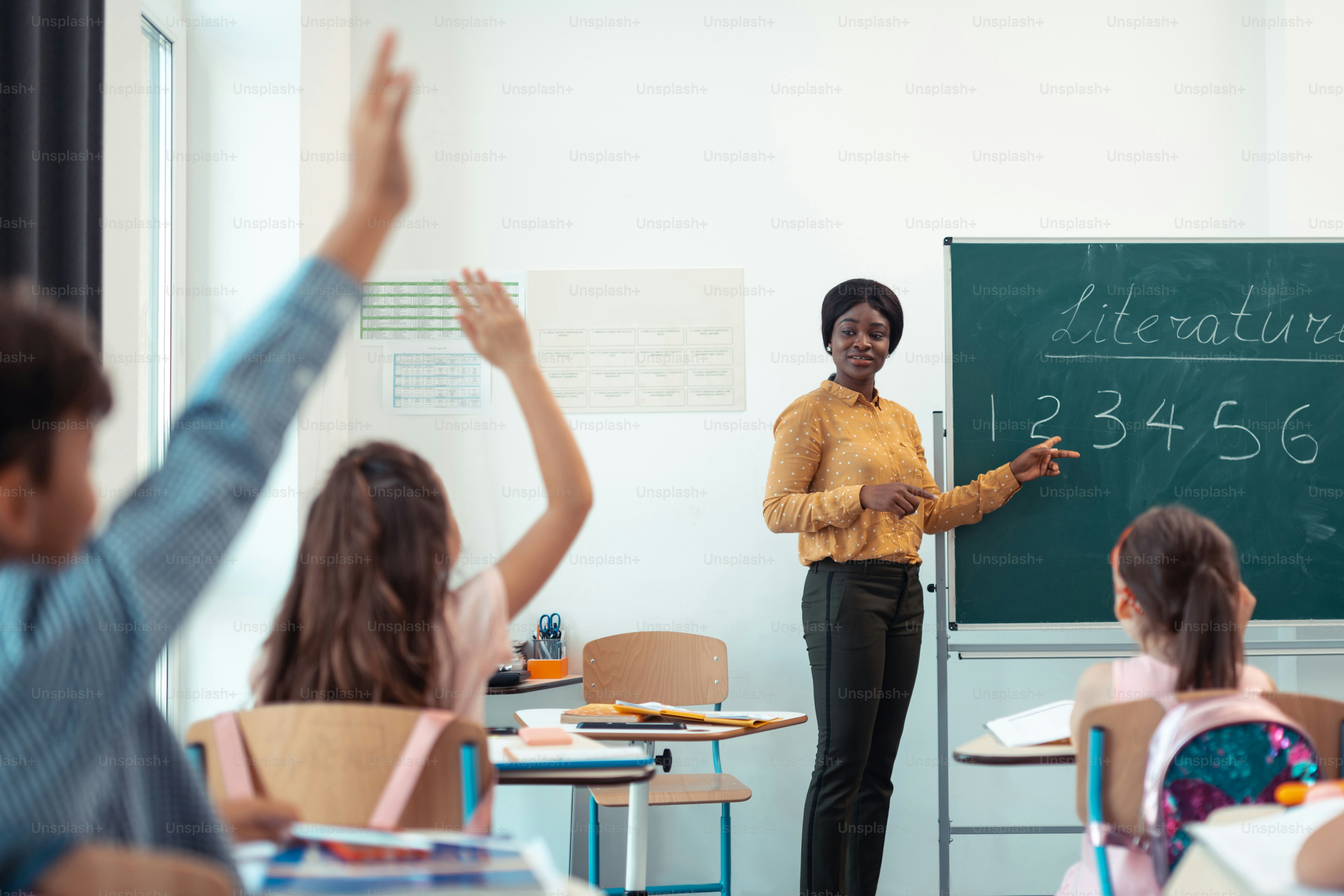 Teacher giving question. Dark-skinned professional teacher giving the question for her smart pupils