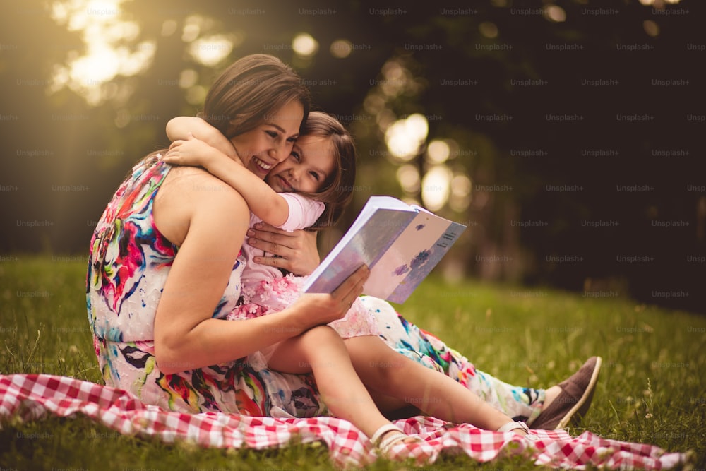 Giving her little girl the gift of literacy. Mother and daughter in nature.