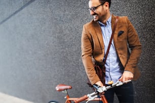 Happy business man with bicycle to work on urban street in city. Transport and healthy lifestyle concept