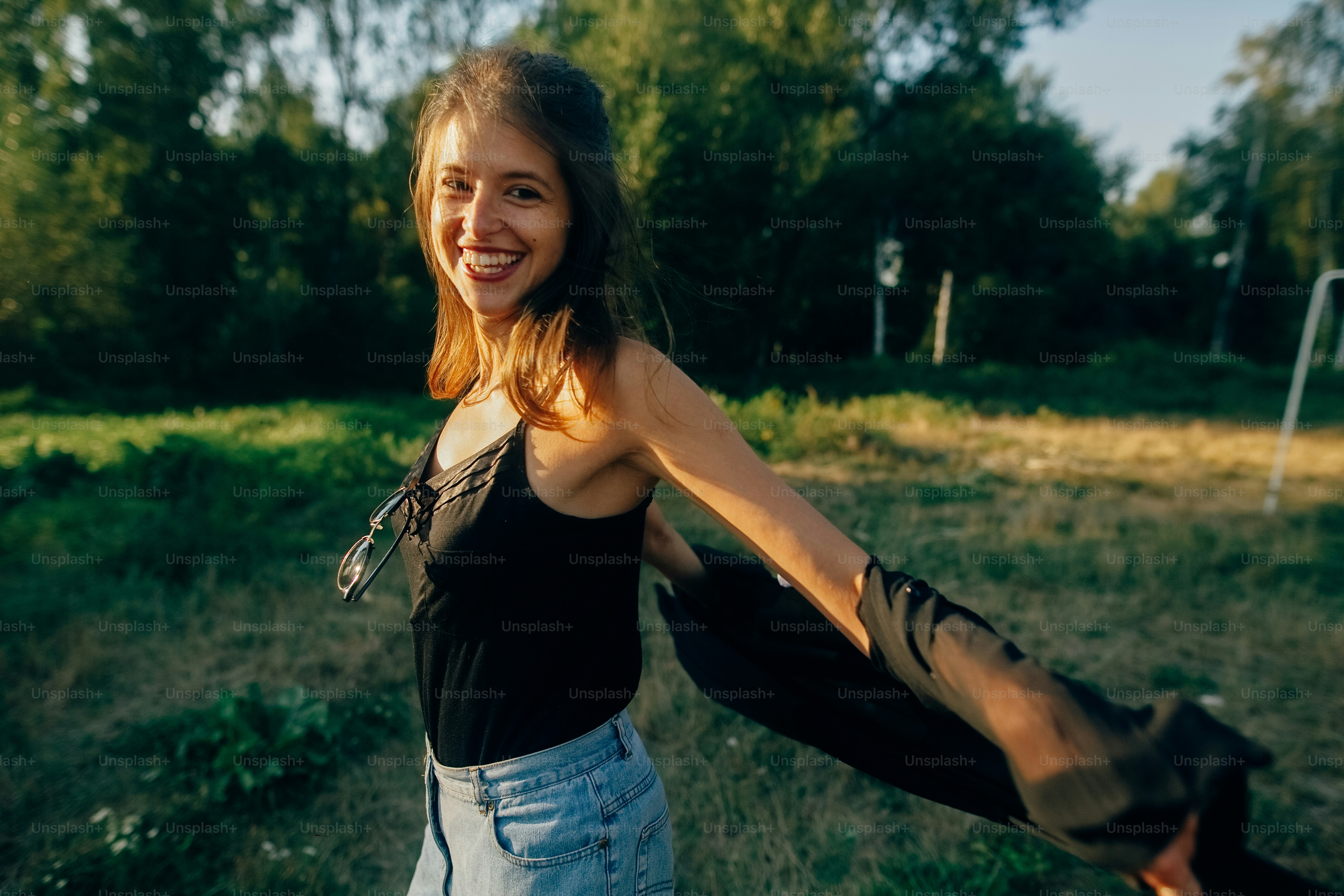 Stylish hipster girl having fun in sunny park in amazing sunbeams, atmospheric moment. Fashionable cool woman dancing and smiling in evening light. Selective focus. Retro effect. Creative image