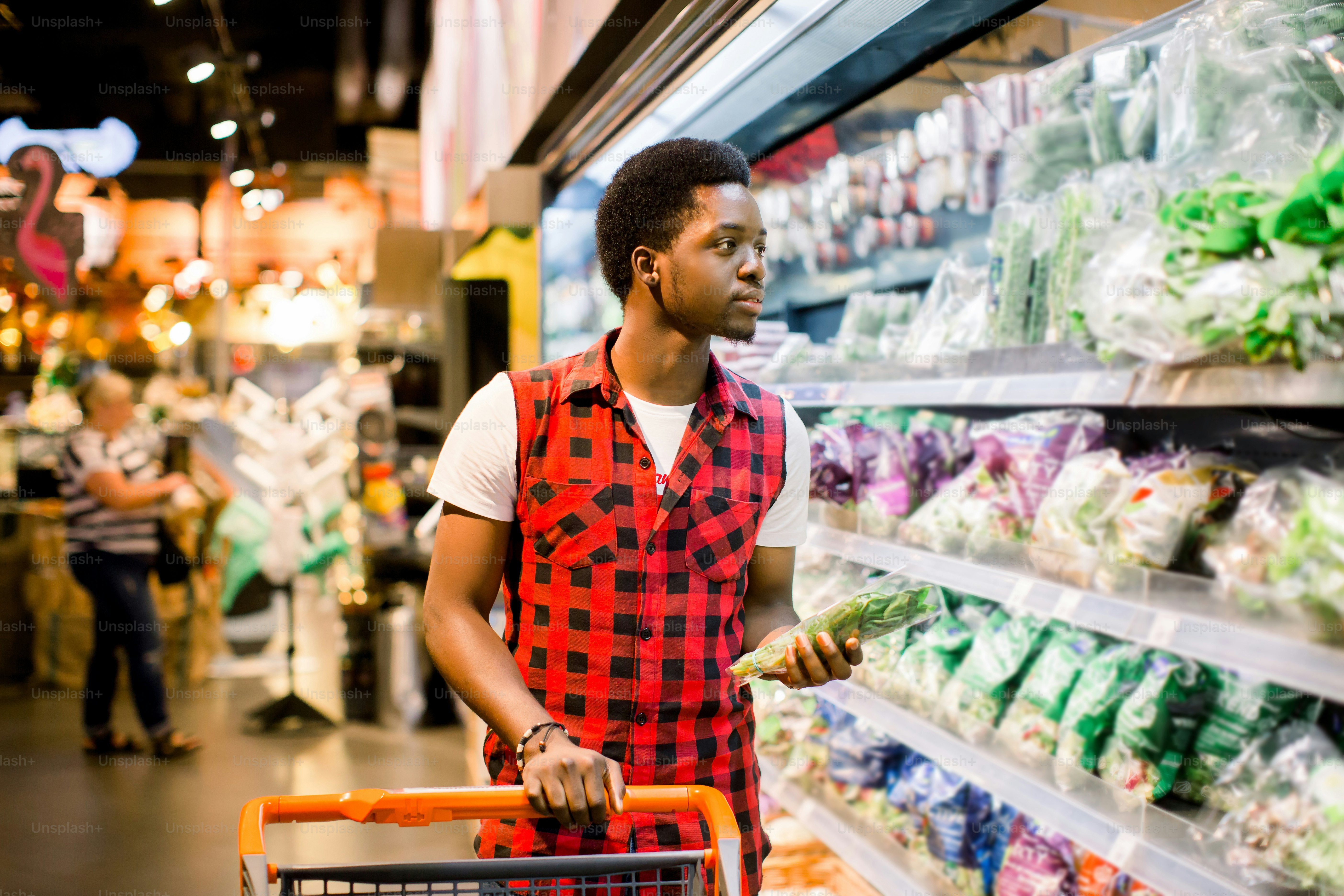 Man Pushing Trolley By Produce Counter In Supermarket