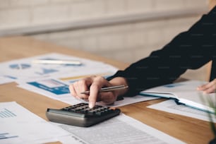 Close up Business woman using calculator for do math finance on wooden desk in office and business working background, tax, accounting, statistics and analytic research concept