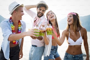 Gruppe von Freunden, die gemeinsam Spaß am Strand haben und Cocktails trinken