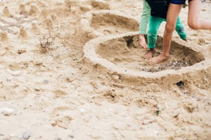 Niños haciendo castillo de arena en la playa. Familia feliz y niños jugando en la arena, haciendo paredes de castillo de arena cerca del mar. Veraneo