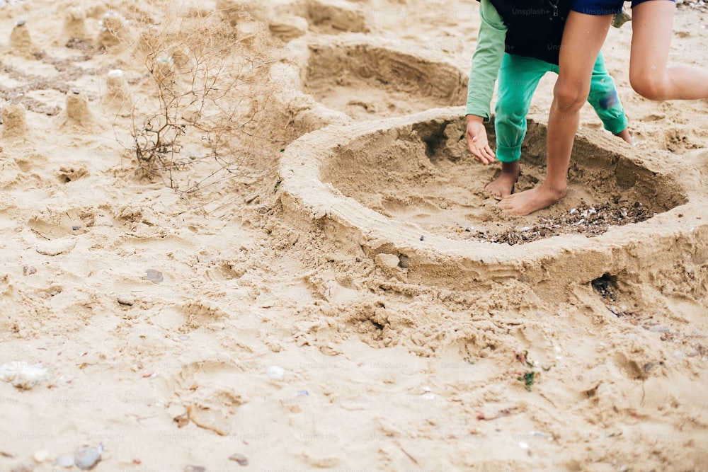 해변에서 모래성을 만드는 아이들. 행복한 가족과 아이들이 모래 위에서 놀고 바다 근처에 모래성의 벽을 만듭니다. 여름방학