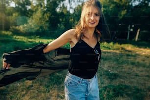 Stylish hipster girl posing in sunny park with amazing sun beams, atmospheric moment. Fashionable cool woman relaxing and smiling  in evening. Selective focus. Retro effect. Creative image