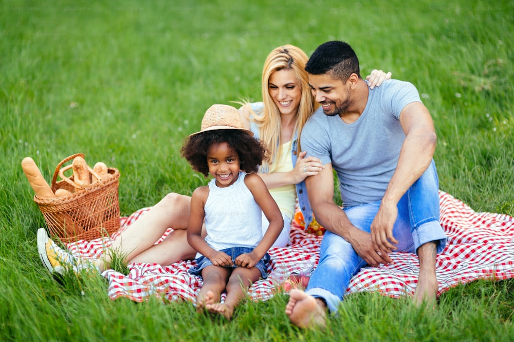 Picture of lovely couple with their daughter having picnic in nature