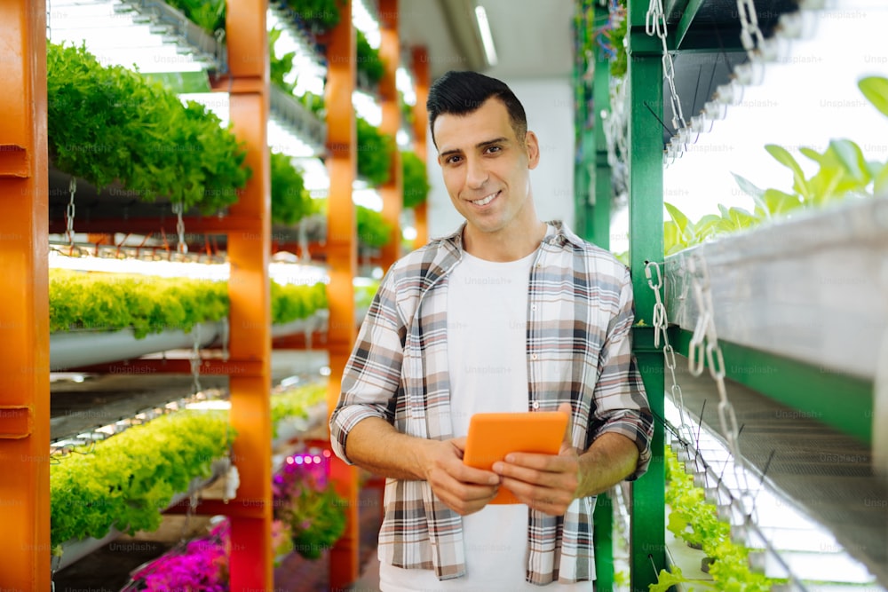 Agricultor sonriendo. Agricultor profesional de ojos oscuros sonriendo mientras comienza un proyecto exitoso