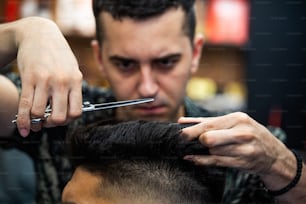 Barbería. Primer plano del corte de pelo del hombre, el maestro hace el peinado en la peluquería. De cerca, el maestro barbero hace el peinado y el peinado con tijeras. Concepto de barbería.