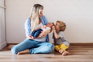 A beautiful young mother with a newborn baby and his toddler brother at home.