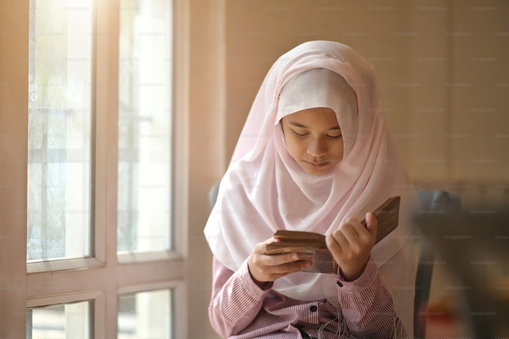Young Asian Muslim girl reading a book.