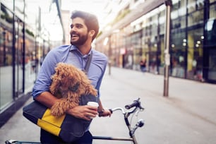Handsome young business man on street drinking coffee with dog