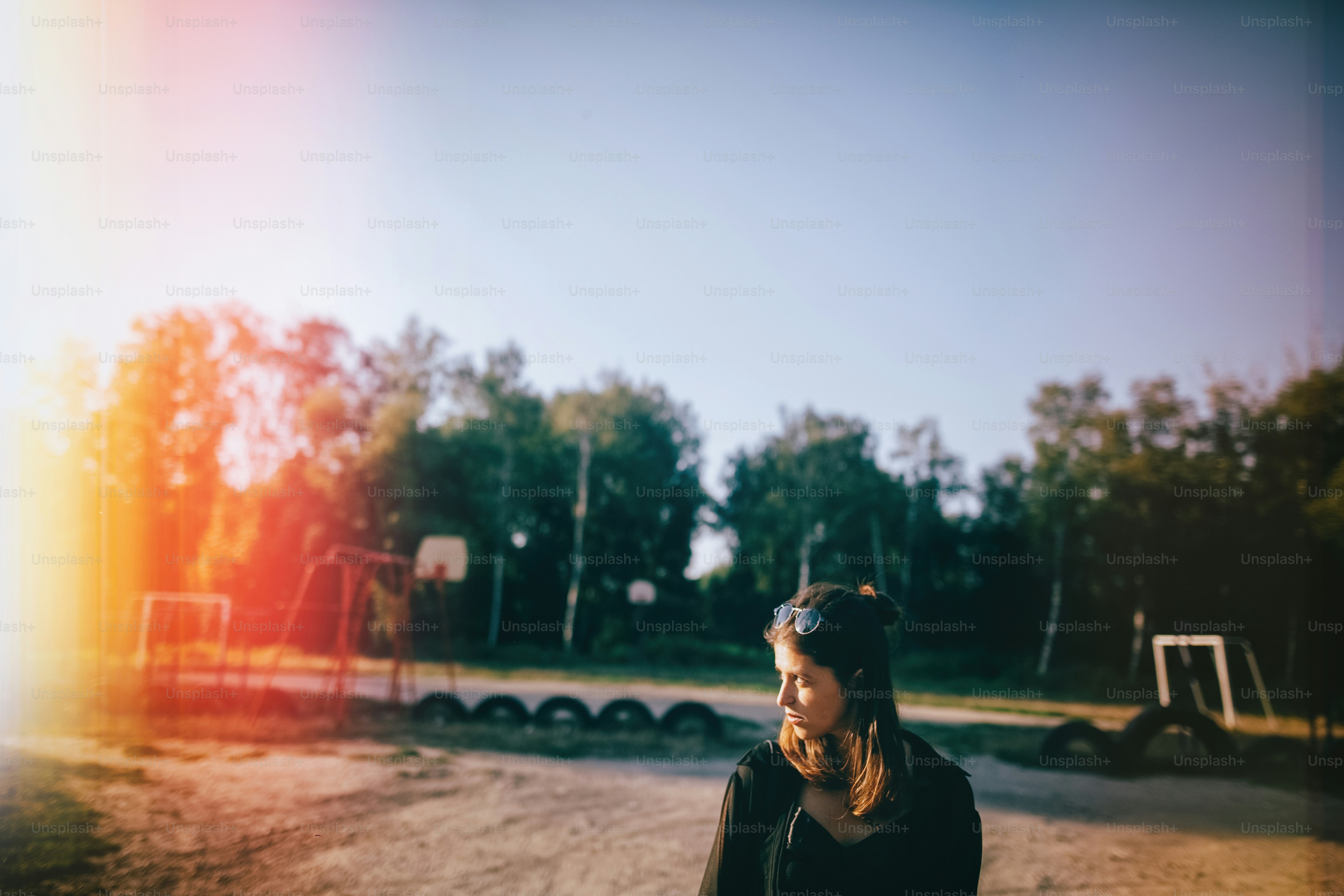 Stylish hipster girl walking in sunny street, atmospheric moment. Fashionable cool woman with black sunglasses and denim jeans relaxing  at playground. Selective focus. Retro effect