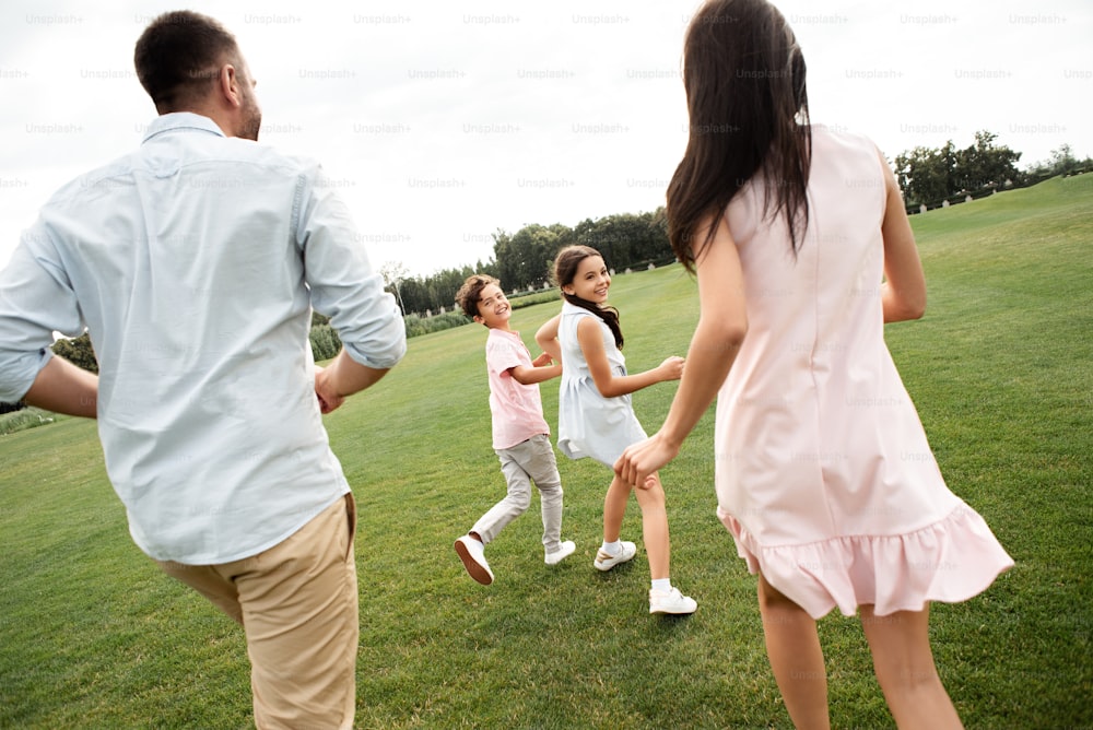 子供と過ごす時間。公園で屋外で家族と自由な時間を過ごしながら一緒に遊んでいる若いアクティブな家族の後ろ姿。ピクニック。週末
