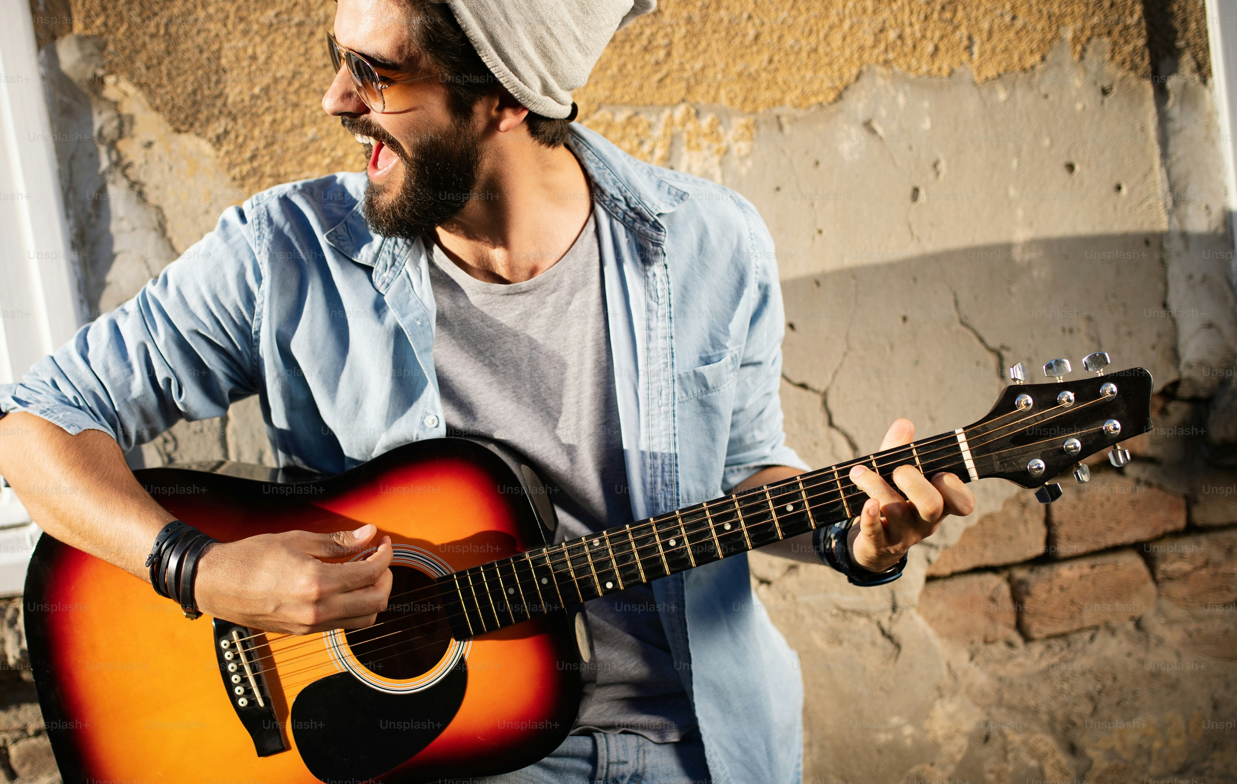 Hombre guapo tocando la guitarra en la calle en un día soleado
