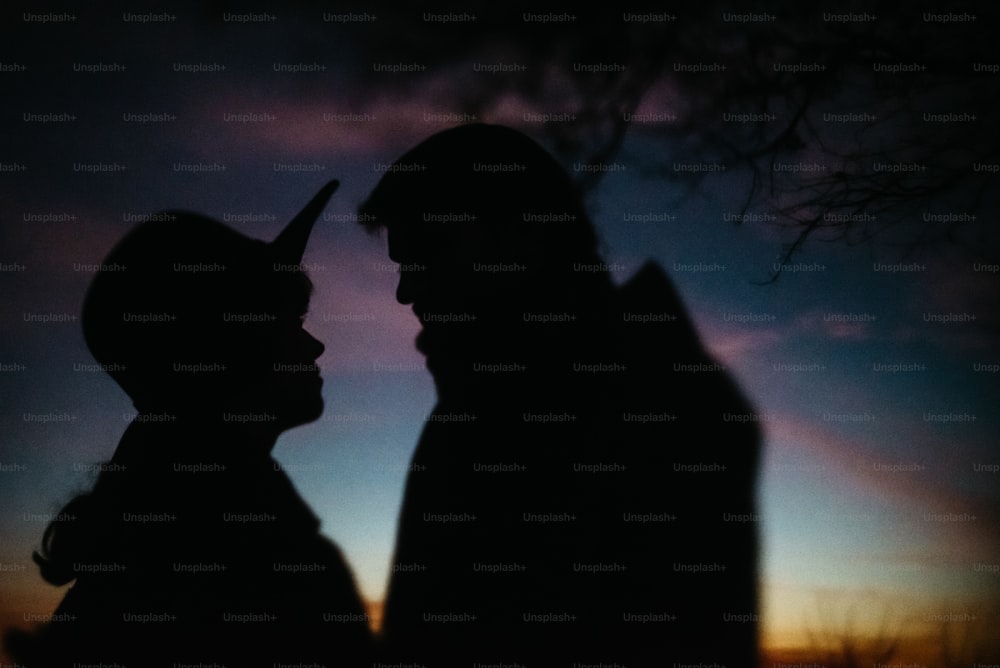 silhouette d’un couple heureux se regardant et se touchant avec douceur sur le fond du ciel de coucher de soleil et des lumières de la ville