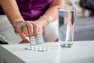Close Up da mulher sênior que toma pílulas de comprimido de suplemento de cálcio e óleo de ômega 3 com copo de água. Suplementos nutricionais.Sport,Diet Concept.Capsules Vitamina e suplementos dietéticos.