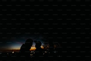 Silhouette des glücklichen Paares, das sich gegenseitig anschaut und sich mit sanftem Hintergrund des Sonnenuntergangshimmels und der Stadtlichter berührt