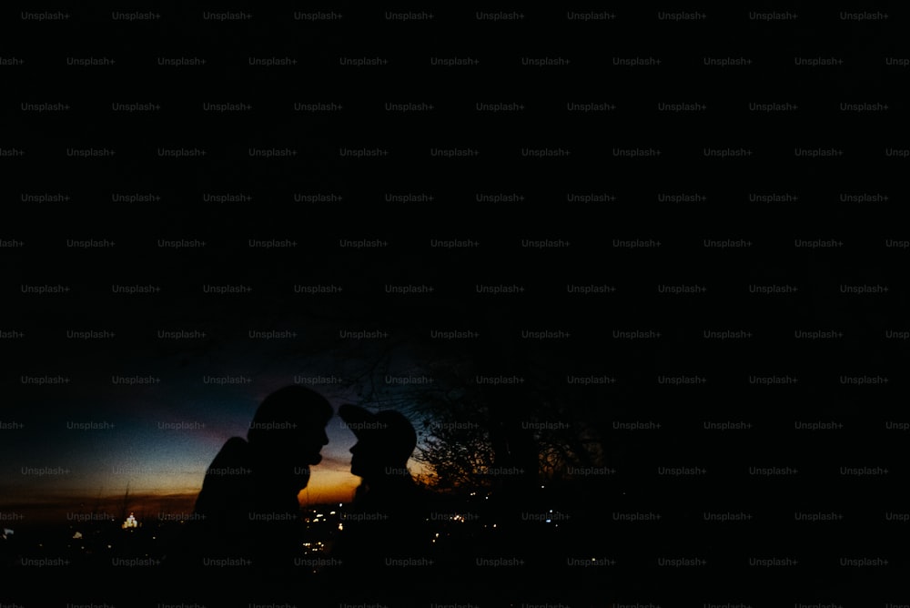silhouette di coppia felice che si guarda e si tocca con delicato sullo sfondo del cielo del tramonto e delle luci della città
