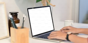 Mãos femininas em close-up digitando em laptop de tela em branco no espaço de trabalho mínimo