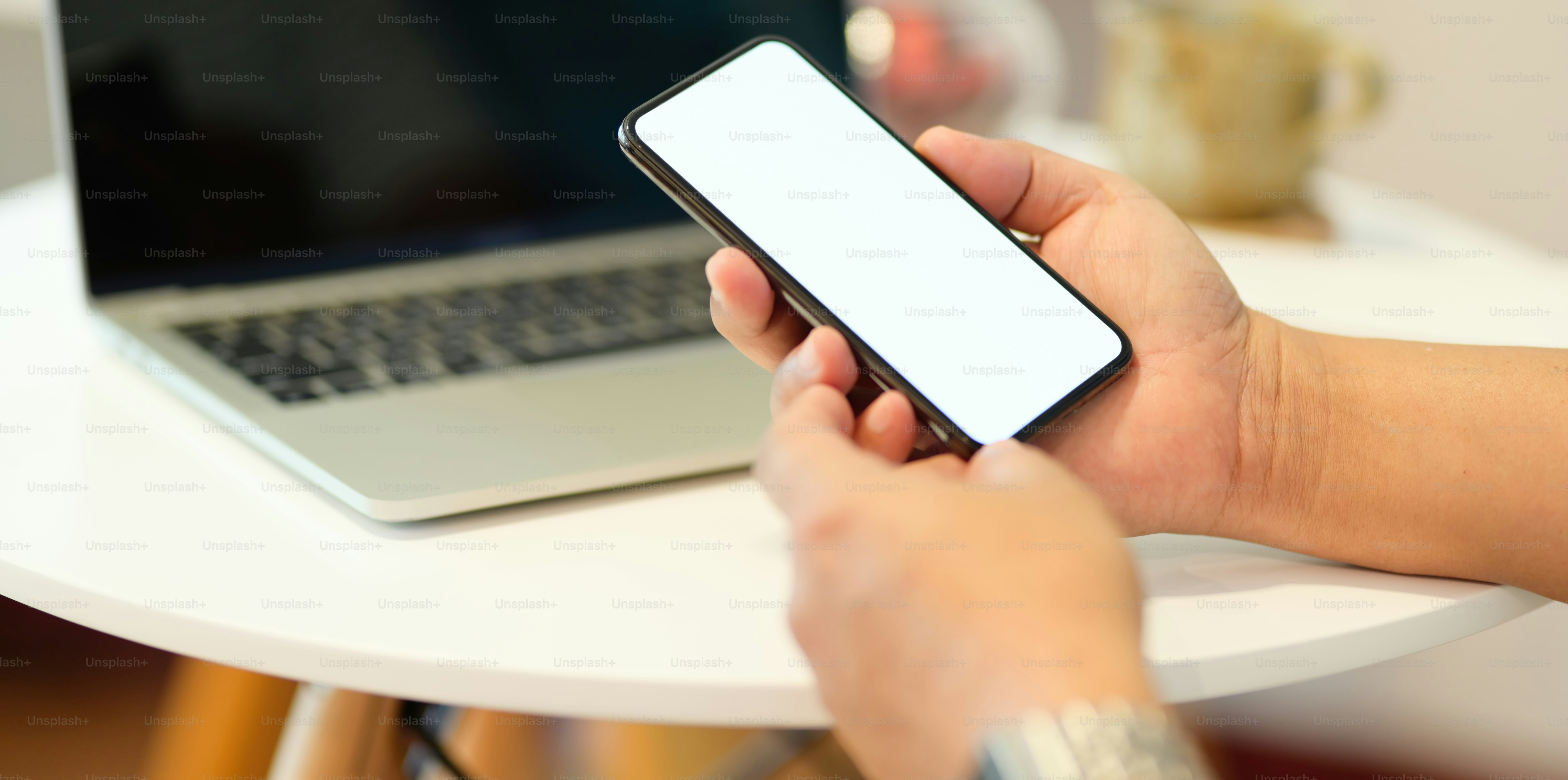 Close up of man's hand holding smartphone with blank screen in comfort workspace