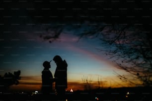 silhouette of happy couple looking at each other and touching with gentle on background of sunset sky and city lights