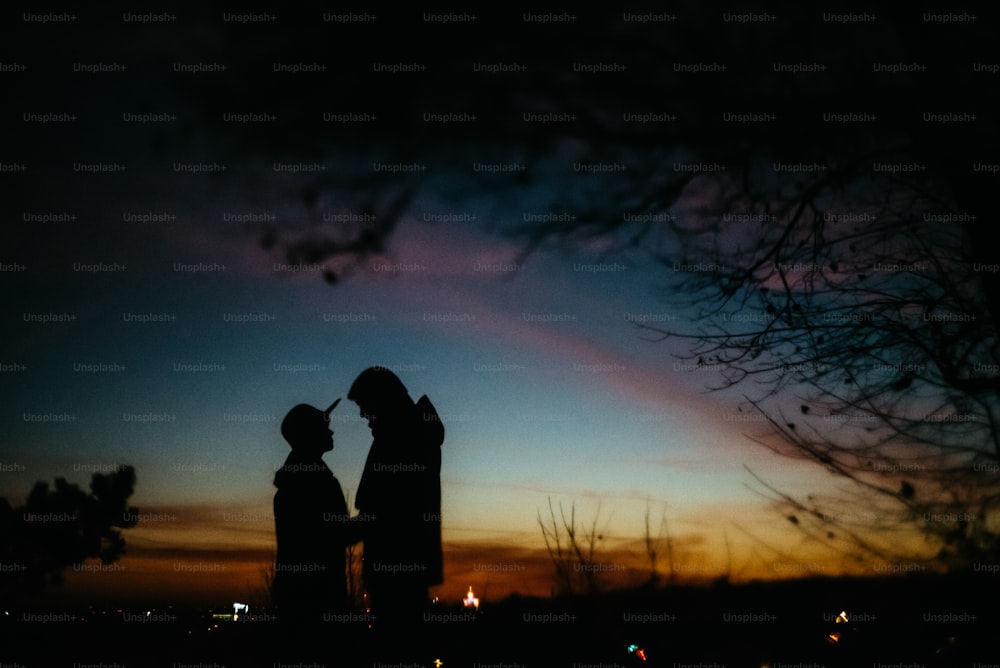 silhouette d’un couple heureux se regardant et se touchant avec douceur sur le fond du ciel de coucher de soleil et des lumières de la ville